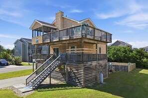 Ein mehrgeschossiges Holzhaus mit Balkon, Treppe und einem eingezäunten Hof.