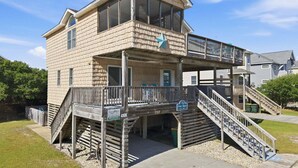 Een gebouw met twee verdiepingen, een balkon, een trap en een bord dat het als een resort identificeert.