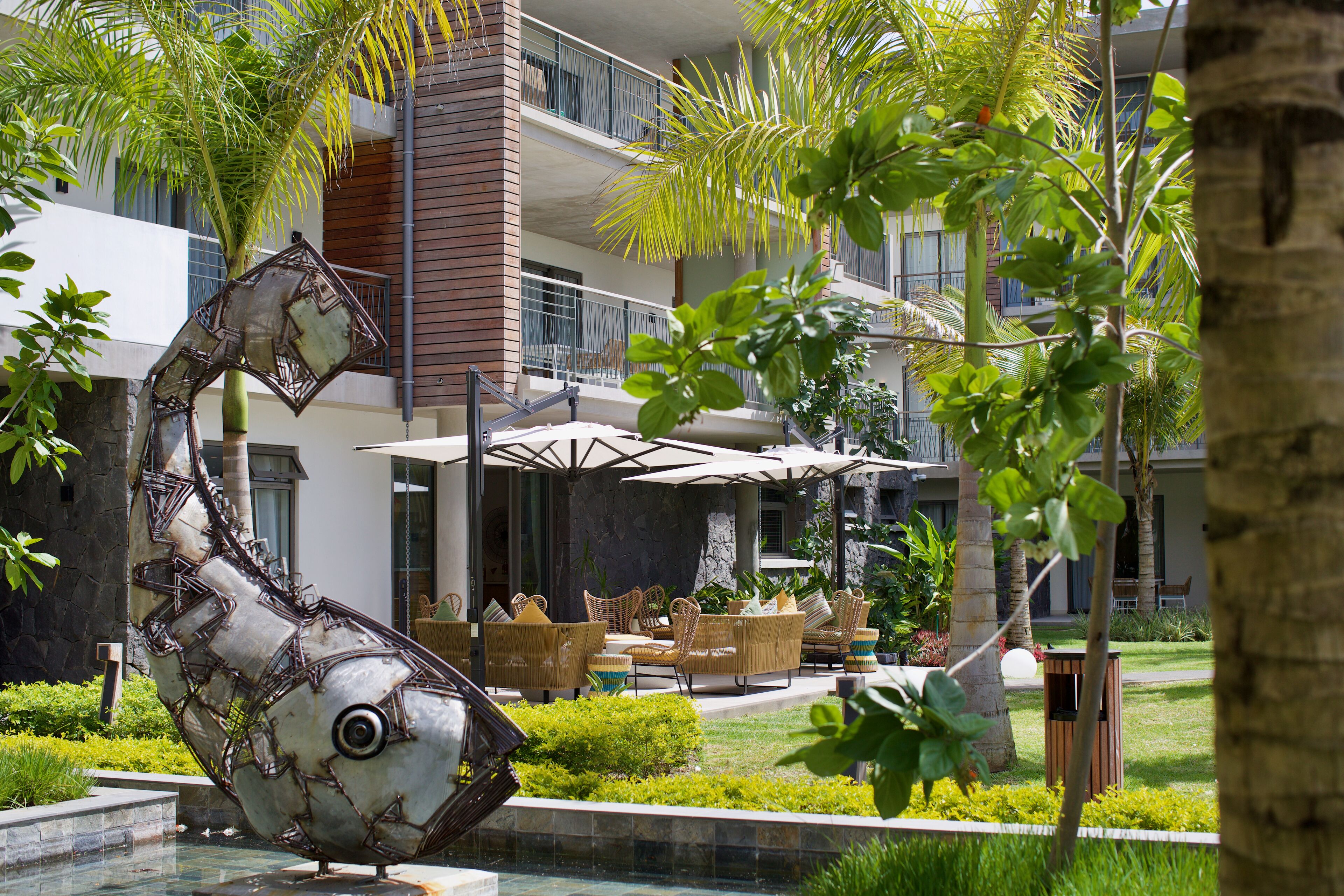 Ein modernes Hotel mit Pool, Sitzgelegenheiten im Freien und einer einzigartigen Metallskulptur.