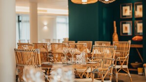 A dining area with wicker chairs and tables set for a meal, featuring hanging pendant lights and framed artwork on the wall. - Domaine de Grand Baie (Mont Choisy)