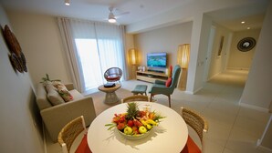 A modern living room with a dining table, chairs, a sofa, a TV, and a fruit bowl. - Domaine de Grand Baie (Mont Choisy)