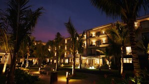 A hotel with multiple floors, palm trees, and outdoor lighting. - Domaine de Grand Baie (Mont Choisy)