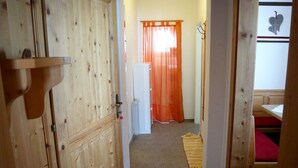 Een houten deur met een knop, een witte radiator, een oranje gordijn, een rood bed en een muur met decoratie in de vorm van een hart.