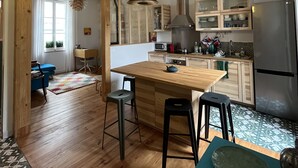 Una cucina moderna con mobili in legno, un'isola centrale, sgabelli da bar e un frigorifero in acciaio inossidabile.