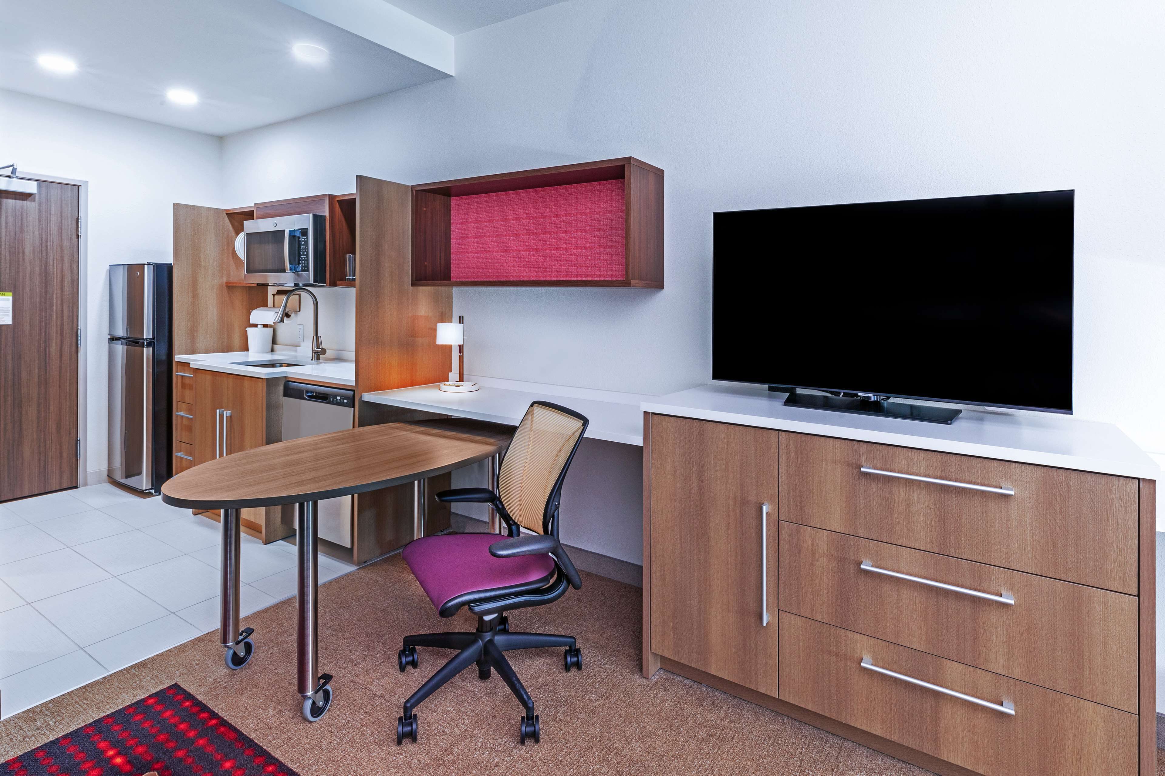 A modern kitchen with a dining area, including a table, chairs, a microwave, and a television.