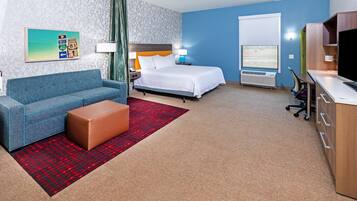 A hotel room with a bed, a sofa, a desk, and a TV.