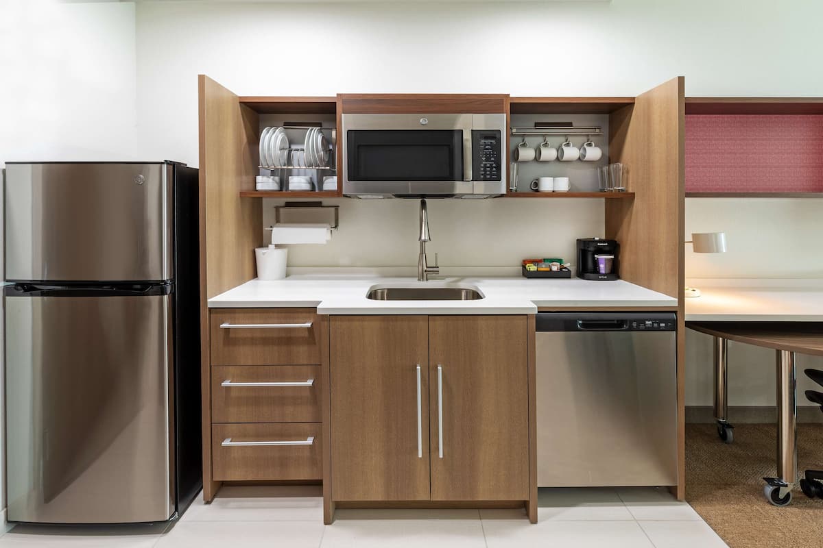 A compact kitchen with a stainless steel refrigerator, a microwave, and a dishwasher.