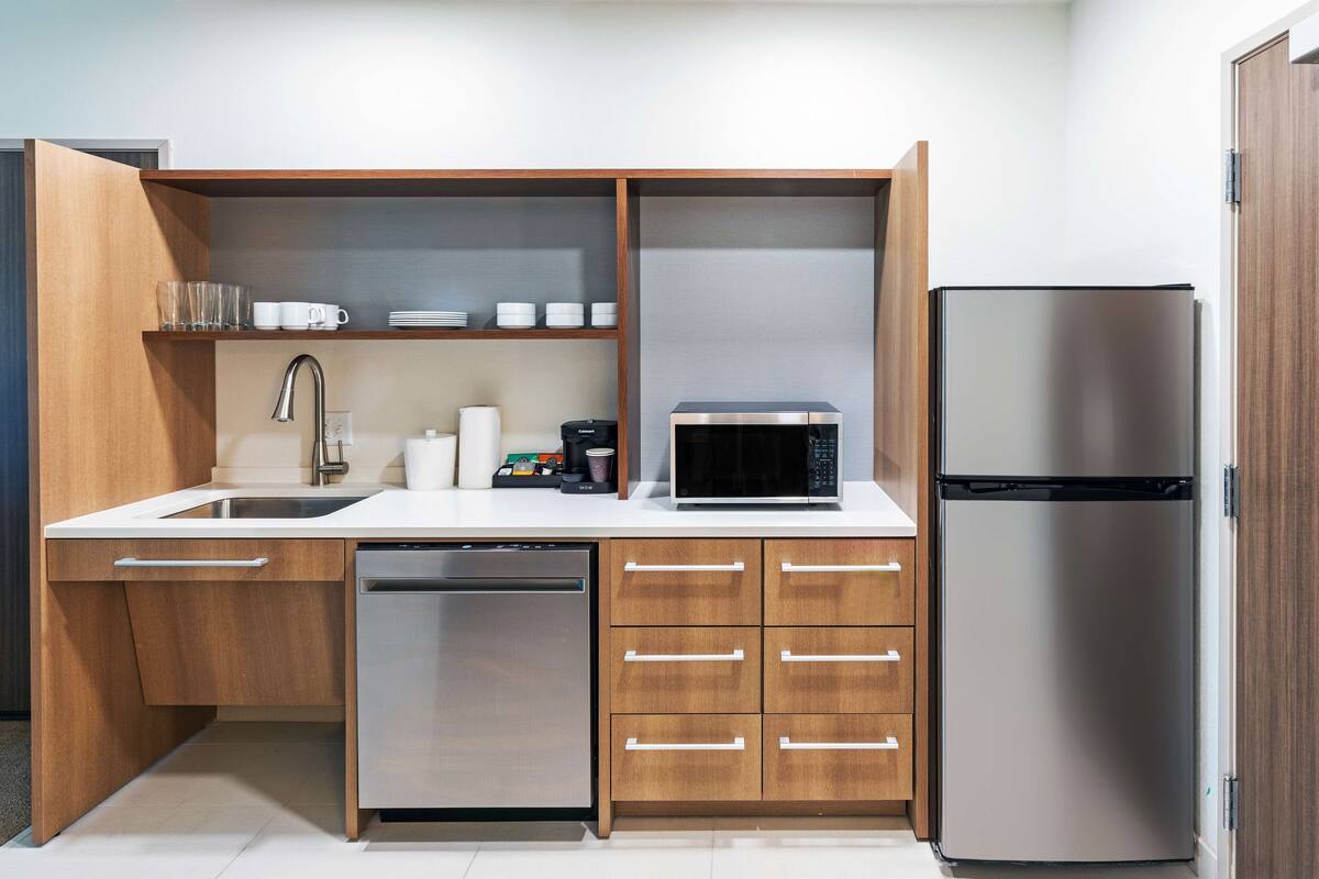 A modern kitchen with a dishwasher, microwave, and refrigerator.
