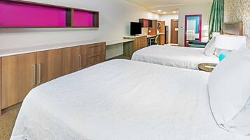 Camera d'albergo con due letti, una scrivania, un televisore e bagno visibile tramite una porta aperta.