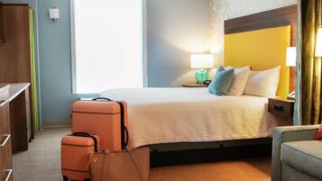 Ein Hotelzimmer mit Bett, Schreibtisch, Stuhl und Koffer.