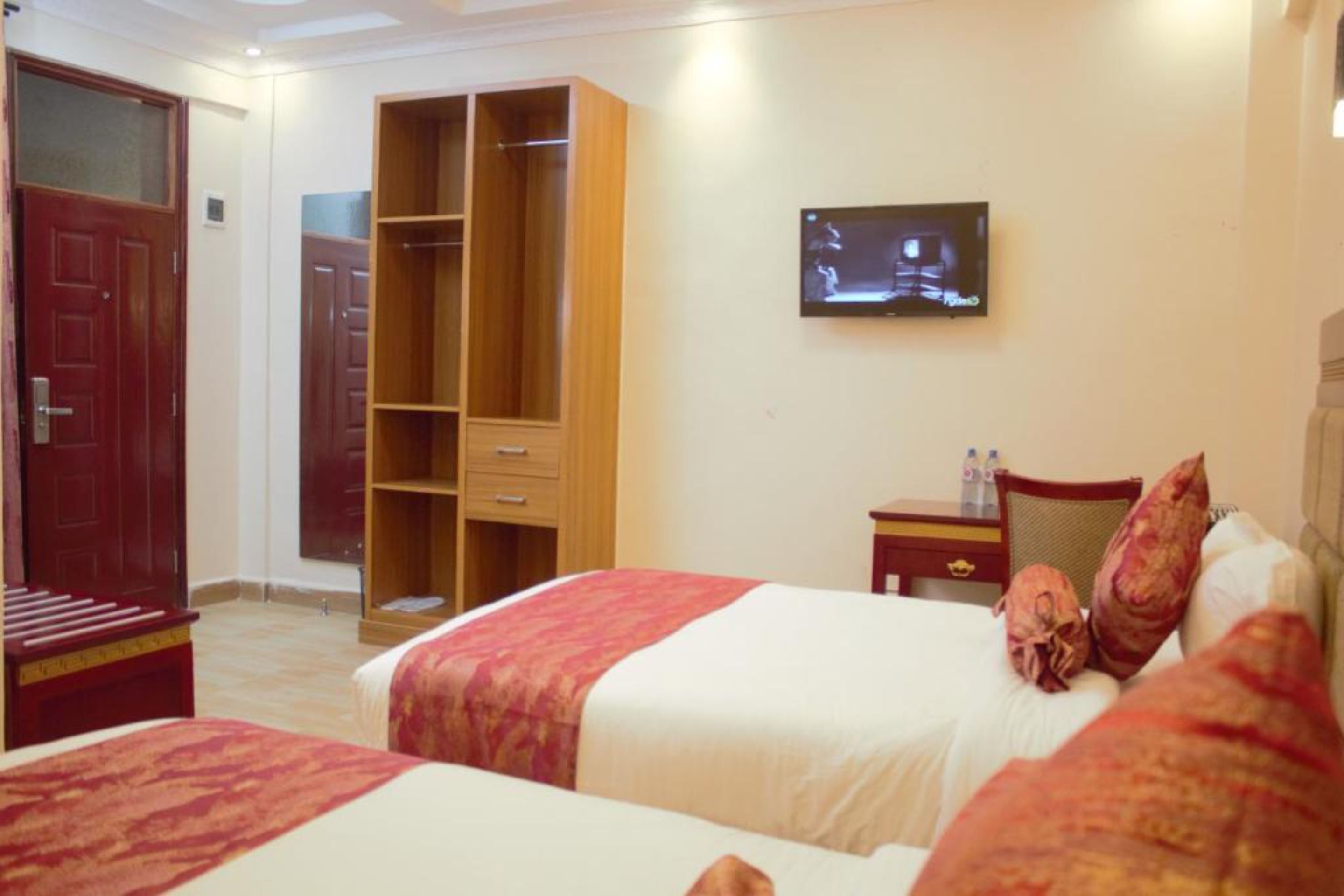 Habitación de hotel con dos camas, televisión, armario y mesita de noche.