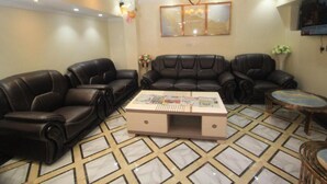 A living room with leather sofas, a coffee table, and a patterned floor. - Vicmark Hotel Nakuru (Nakuru)