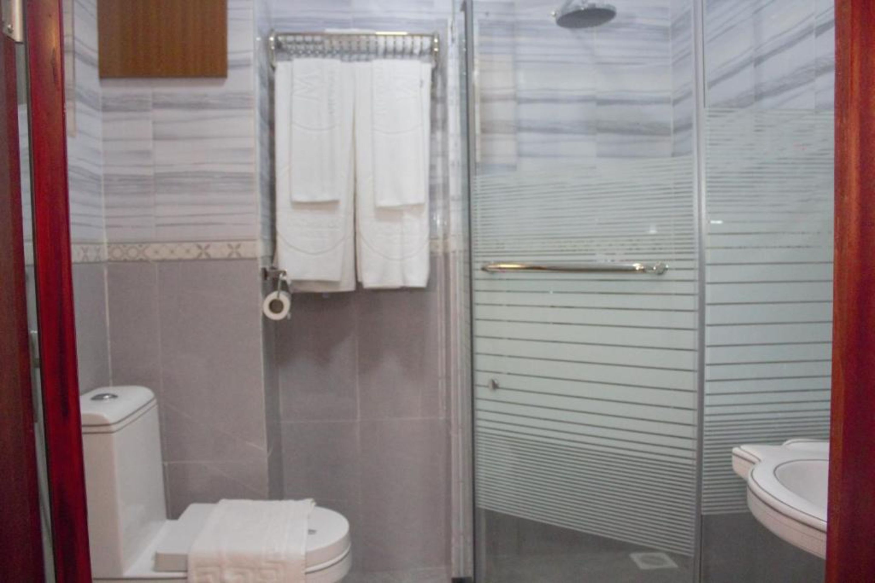 A bathroom with a glass shower enclosure, a toilet, and a sink.