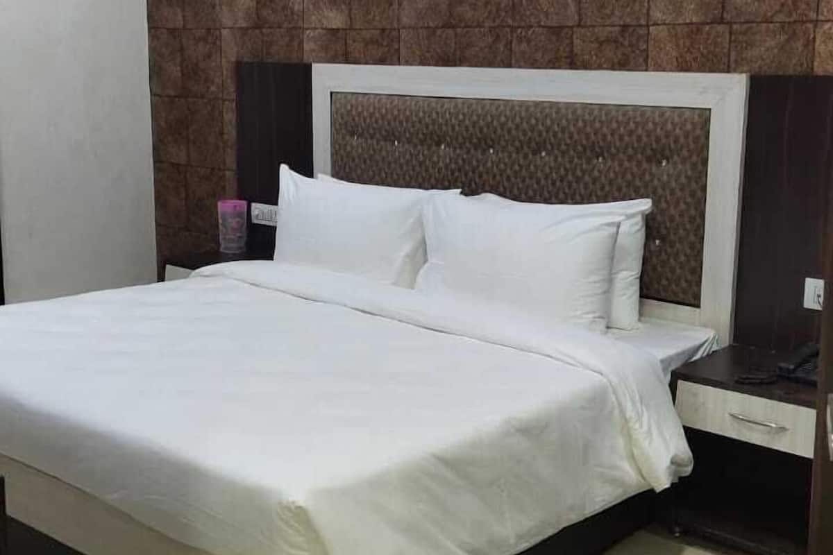 A neatly made bed with white linens in a room with a stone-patterned wall and a modern ceiling design.