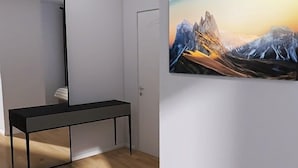 Ein minimalistisch eingerichteter Raum mit einem schwarzen Konsolentisch, einer weißen Tür und einem großen Landschaftsbild an der Wand.