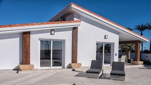 Een modern huis met een zwembad, twee loungesteunen en een overdekt terras.