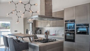 Een moderne keuken met een centraal eiland, roestvrijstalen apparatuur en een bijzondere hanglamp.
