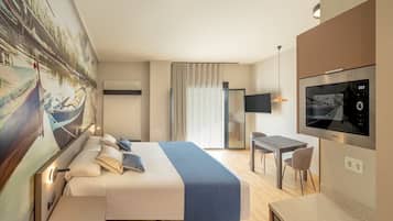 A hotel room with a bed, a desk, a TV, and a painting of a boat on the wall.