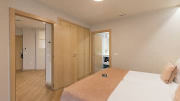 Una habitación de hotel con una cama, un armario de madera y un baño visible a través de una puerta de vidrio.