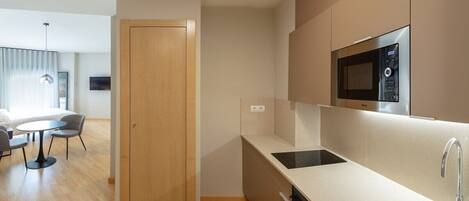 A modern kitchen with a microwave, sink, and a dining area with a table and chairs.