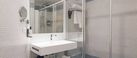 A modern bathroom with a white sink, a large mirror, and a glass shower enclosure.