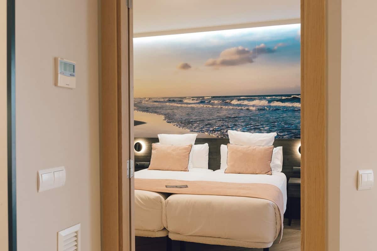A bedroom with a bed, pillows, and a view of the ocean.