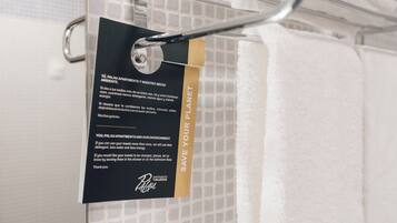 A towel rack with a sign encouraging towel reuse to save the planet.