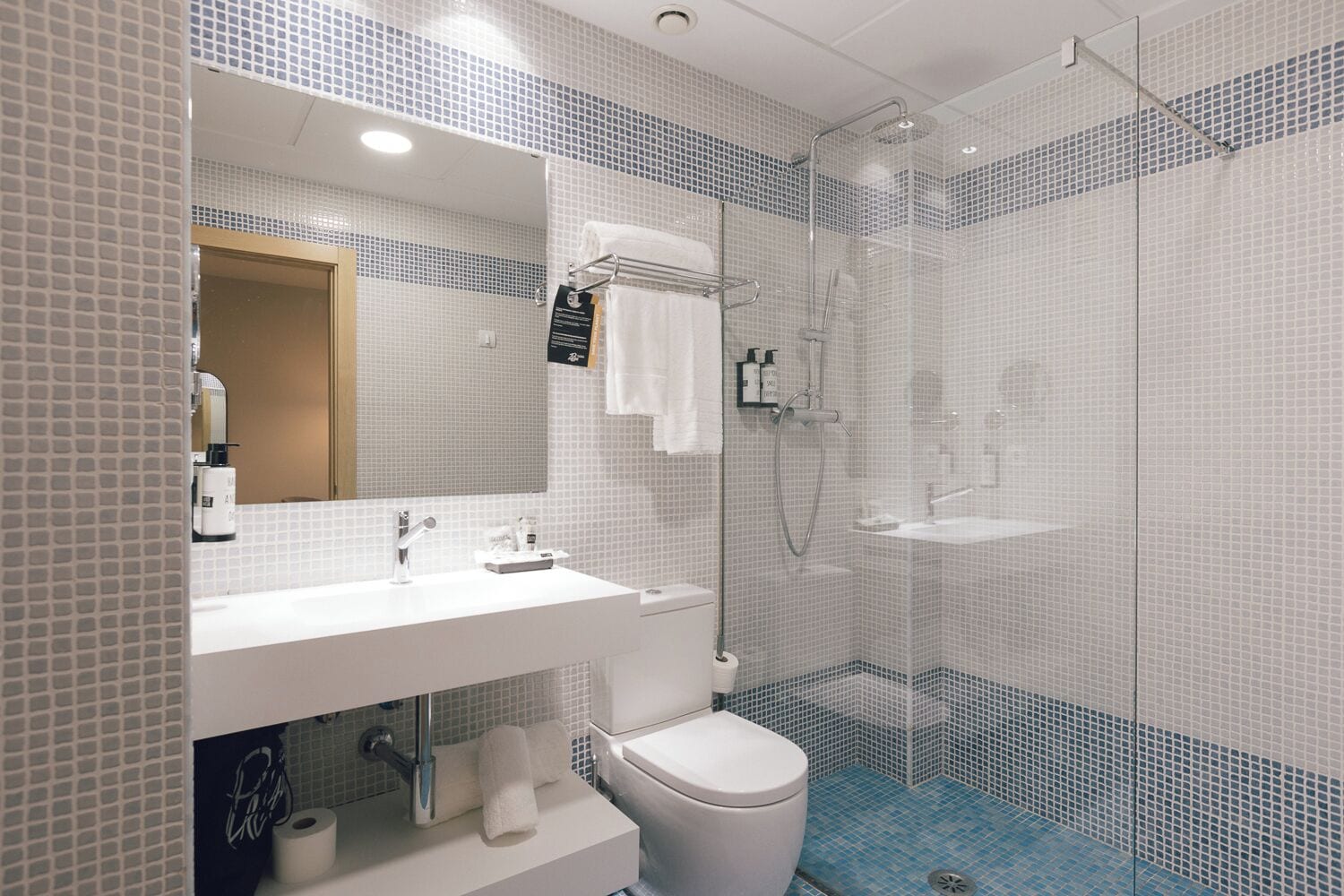 Et moderne badeværelse med hvid vask, toilet og brusebad.