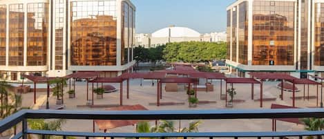 A modern hotel with a rooftop terrace featuring outdoor seating and palm trees.