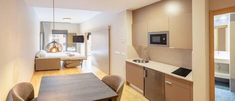 A modern kitchen with a microwave, sink, and wooden dining table.