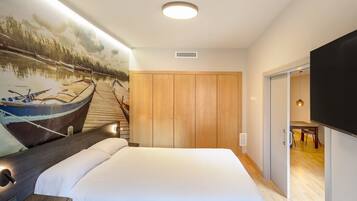 Una camera d'albergo con un letto grande, un armadio in legno, una televisione a schermo piatto e un affresco raffigurante un paesaggio fluviale.