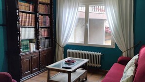 A living room with a wooden bookshelf, a red sofa, a coffee table, and a window with curtains. - Casa Rubén Darío, located in the Sierra de Gredos (suitable for pets) (Villarejo del Valle)