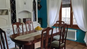 A dining room with a wooden table and chairs, a chandelier, and a window with curtains. - Casa Rubén Darío, located in the Sierra de Gredos (suitable for pets) (Villarejo del Valle)