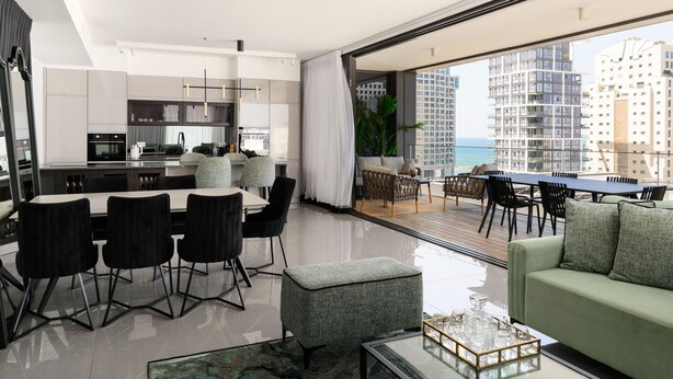 A modern apartment with a kitchen, dining area, and a balcony with a city view. - MAMAD Luxury Executive 4BR with Terrace & Sea View by FeelHome (Tel Aviv - Jaffa)