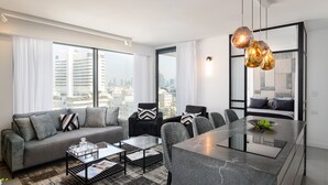 A modern living room with a sofa, coffee table, and dining area. - MAMAD Luxury Executive 4BR with Terrace & Sea View by FeelHome (Tel Aviv - Jaffa)