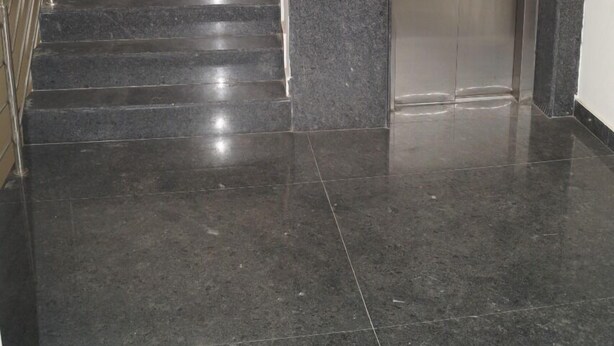A modern elevator with a metallic finish, a marble-tiled floor, and a metal staircase with handrails. - BSK Deluxe Lodging (Bengaluru)