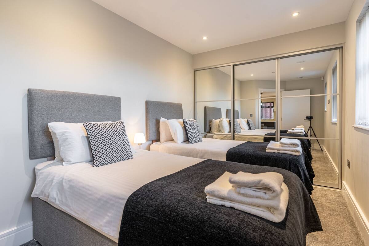 A hotel room with two beds, a large mirror, and a camera on a tripod.