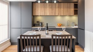 Una cocina moderna con gabinetes grises, detalles de madera e iluminación colgante.