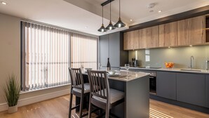 Una cocina moderna con una isla central, armarios de madera e iluminación colgante.