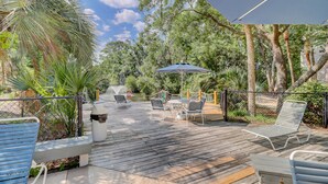 An outdoor patio with wooden flooring, metal chairs, and a table. - 2 BR Treetops First Floor easy to access Bikes & Beach Gear included (Hilton Head Island)