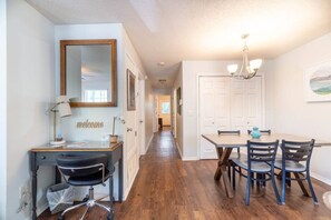 A hallway with a desk, chair, and a dining table with chairs.