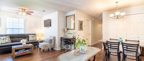 A living room with a sofa, coffee table, and a dining area with a table and chairs.