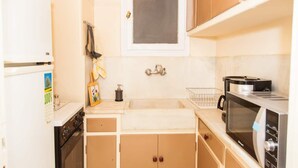 A compact kitchen with a stove, sink, and microwave. - Renovated apt in the Heart of Piraeus (Piraeus)