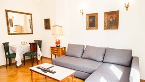 A living room with a grey sofa, wooden coffee table, and a dining table with chairs. - Renovated apt in the Heart of Piraeus (Piraeus)