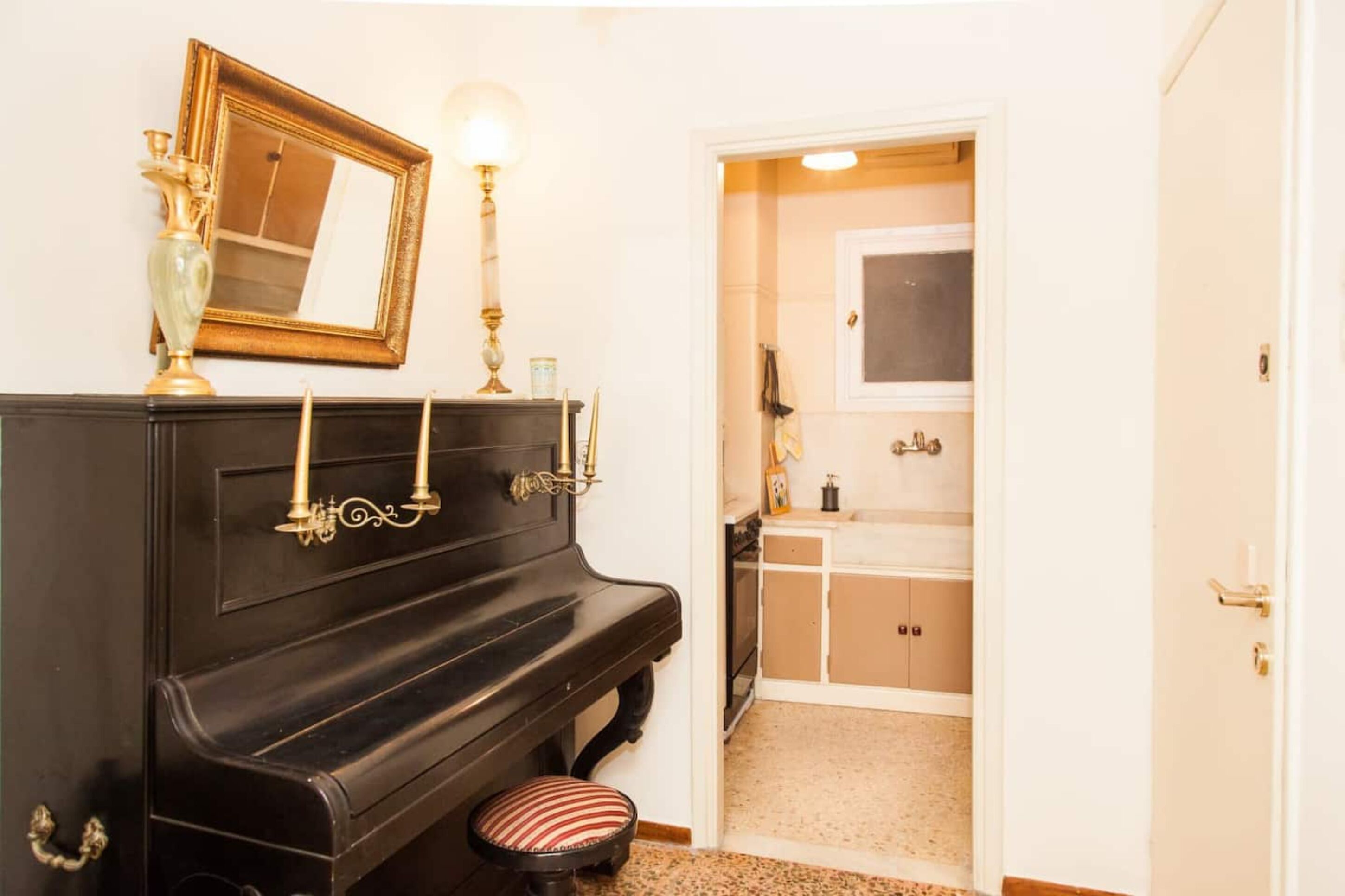 A room with a black piano, a mirror, and a small stool.