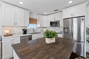 Una cocina moderna con armarios blancos, electrodomésticos de acero inoxidable y una isla de madera.