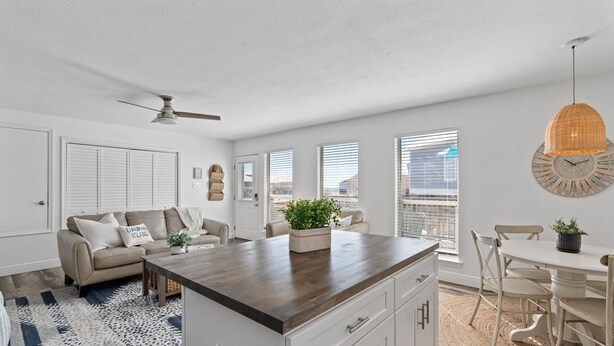 Een moderne keuken met een centraal eiland, witte kasten en een eethoek met een witte tafel en stoelen.