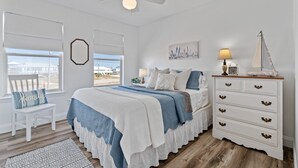Een slaapkamer met een bed, een kaptafel, een stoel en een raam met uitzicht.