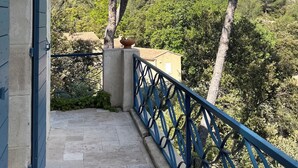 Un balcon donnant sur une colline, avec une balustrade et un pot de fleurs.