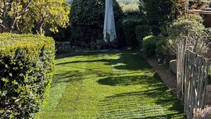 Un jardin bien entretenu, avec une pelouse, un grand arbre et un mur de pierres.